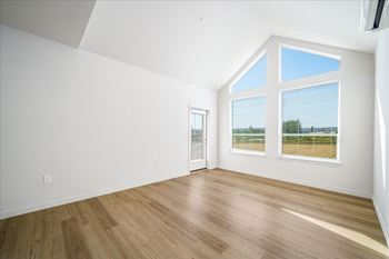 A room with a wooden floor and a large window with blinds.